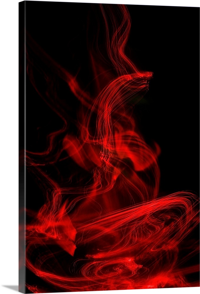 Long exposure abstract photograph of red light trails resembling smoke with a black background.