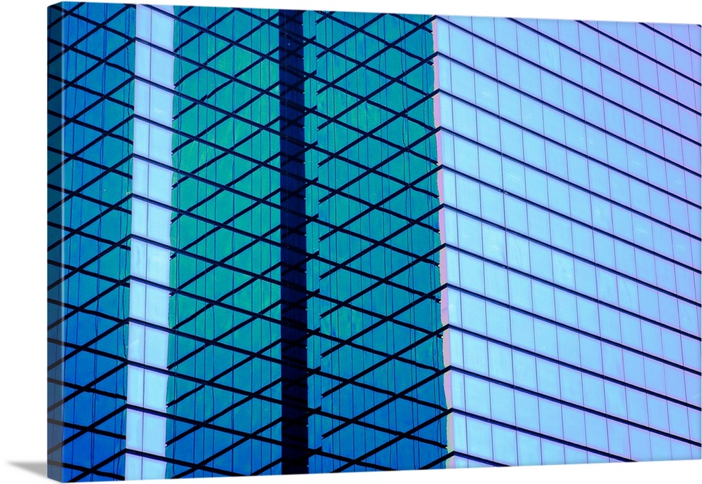 Architectural abstract photograph of the side of a glass building with the blue sky reflecting off of it.