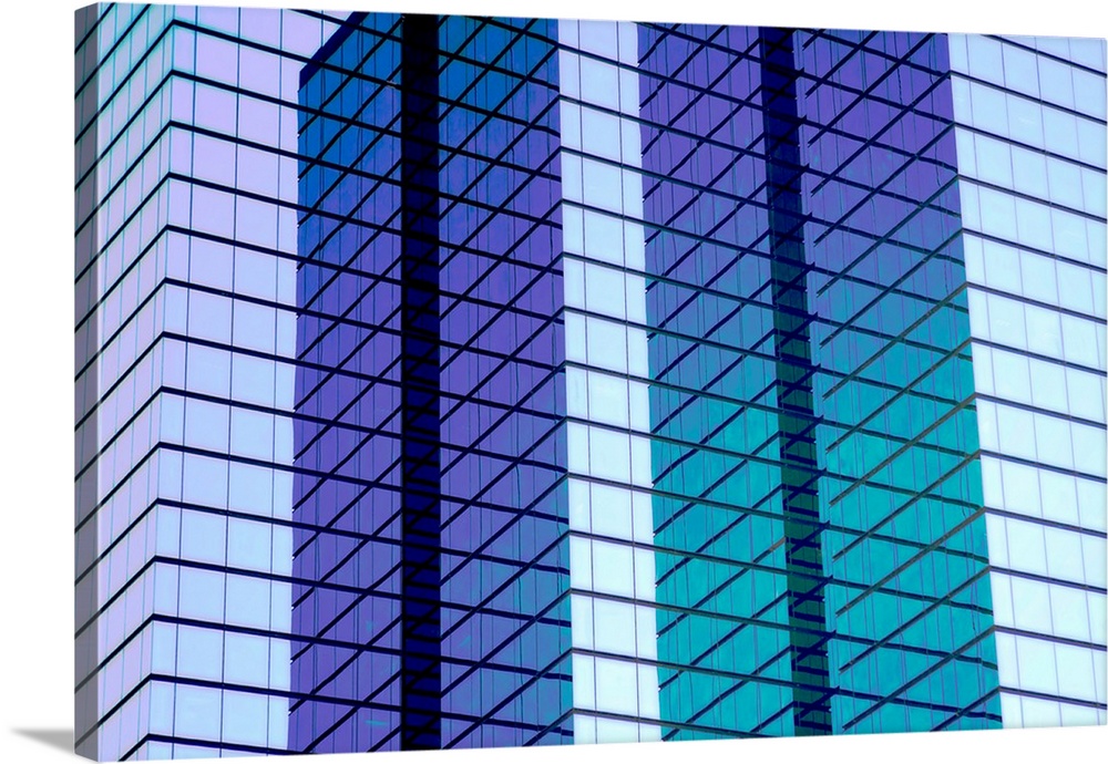 Architectural abstract photograph of the side of a glass building reflecting the blue sky.