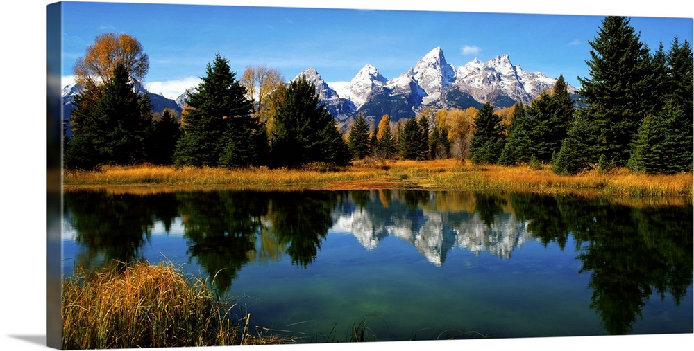 Panoramic view of the Grand Tetons reflected in a lake in Wyoming.