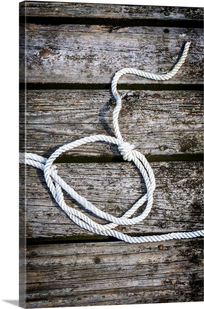 Photograph of a white rope looped and tied with a knot on a wooden background.