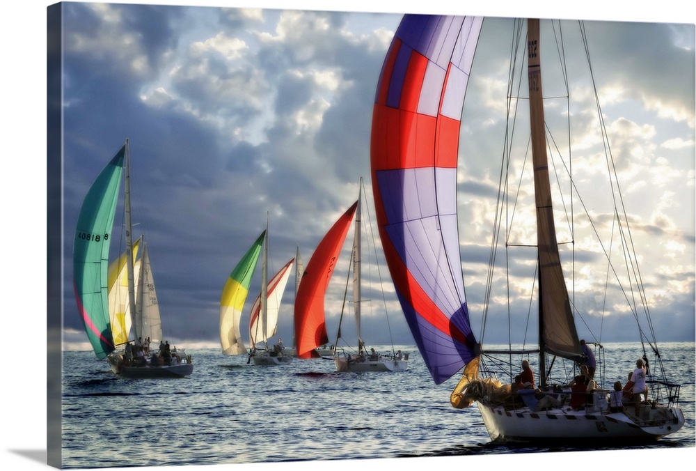 Several sailboats with colorful sails under a cloudy sky in the evening.