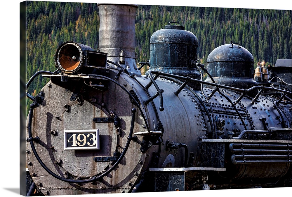 Photograph of the front of an old train engine in a rail yard.