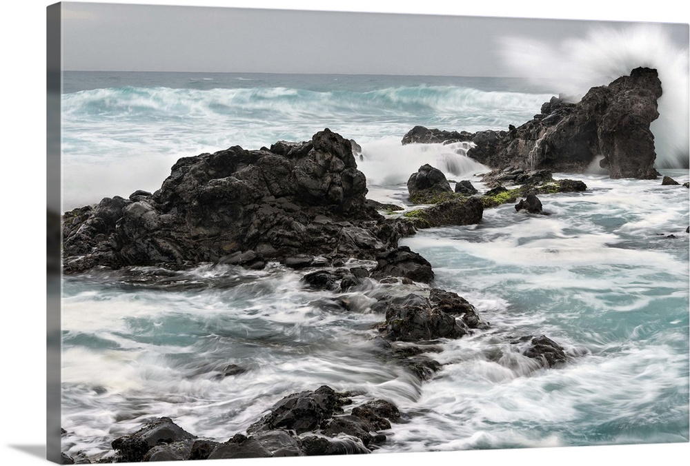 Photograph of waves crashing on large rocks at Ho'okipa beach in Hawaii.