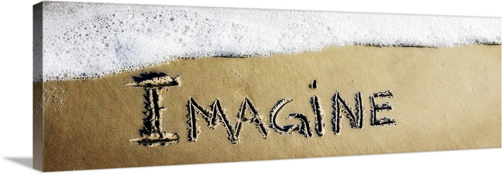 The word "Imagine" drawn in the sand near the ocean water.