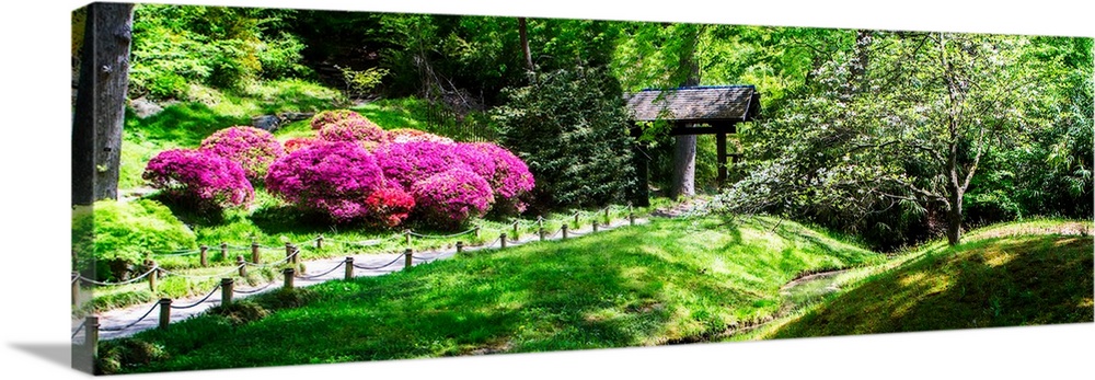 Panoramic photograph of a Japanese garden with bright pink and purple flowers and lush greenery.