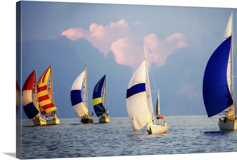 A regatta of colorful sailboats with a cloudy sky.