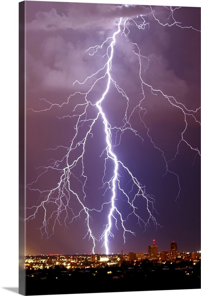 Photograph of large lightning bolts striking in a purple sky above an Arizona city.