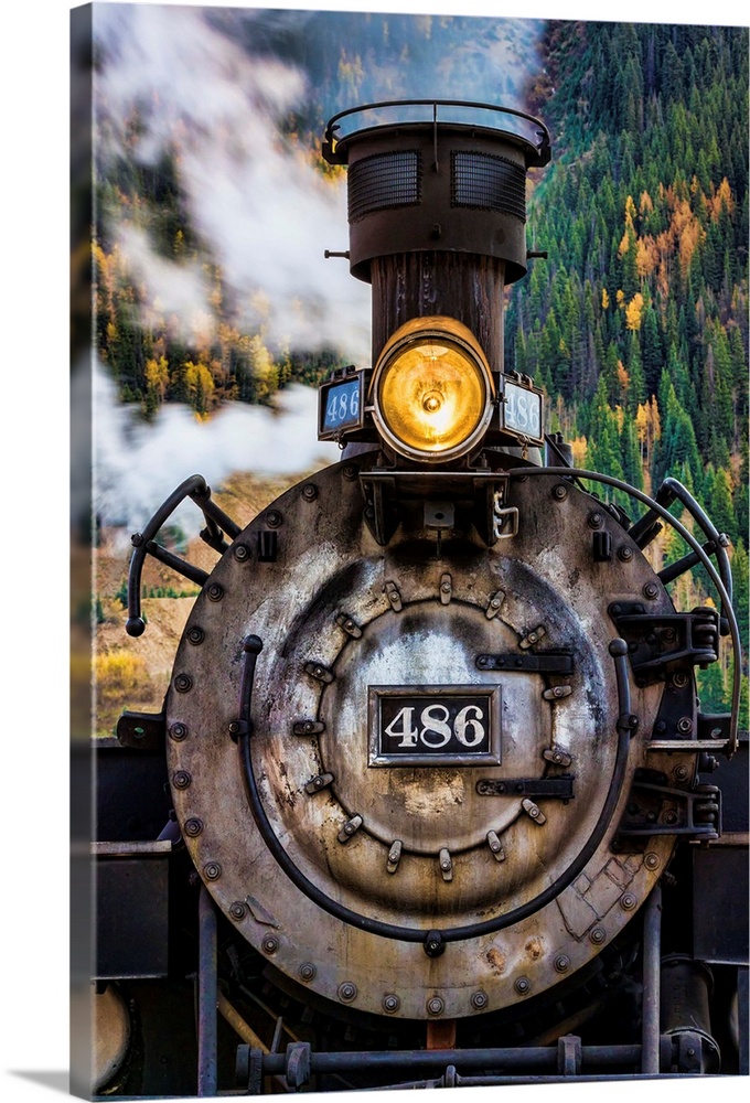 Photograph of the front of an old train engine with steam.