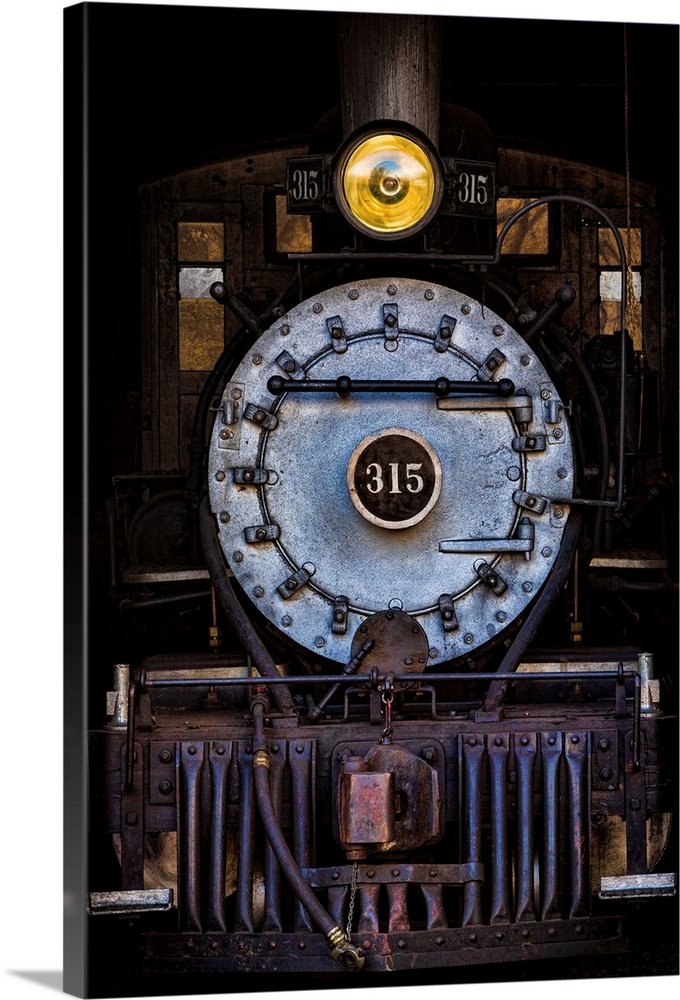 Photograph of the front of an old train engine in the dark.