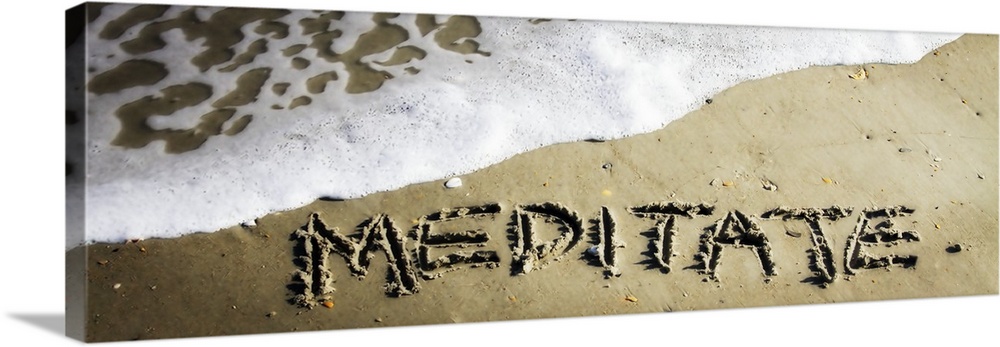 The word "Meditate" drawn in the wet sand near ocean water.