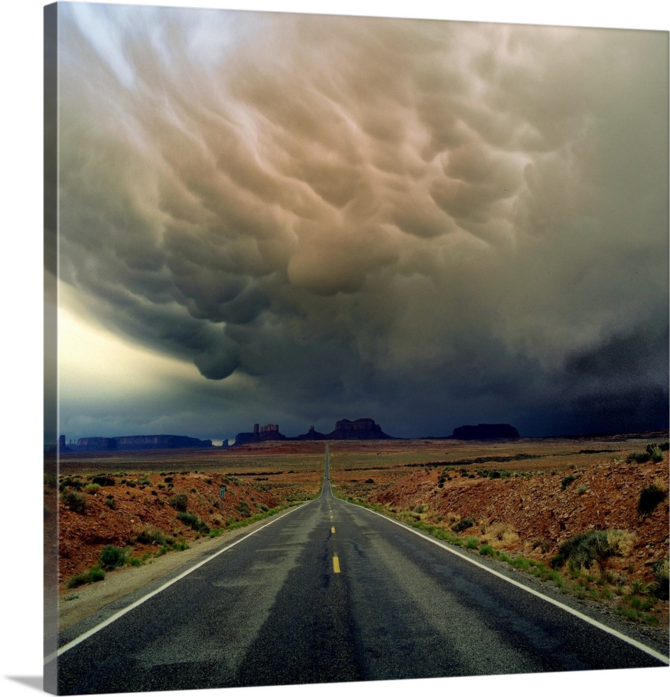Heavy storm clouds over a road through the desert in Monument Valley.