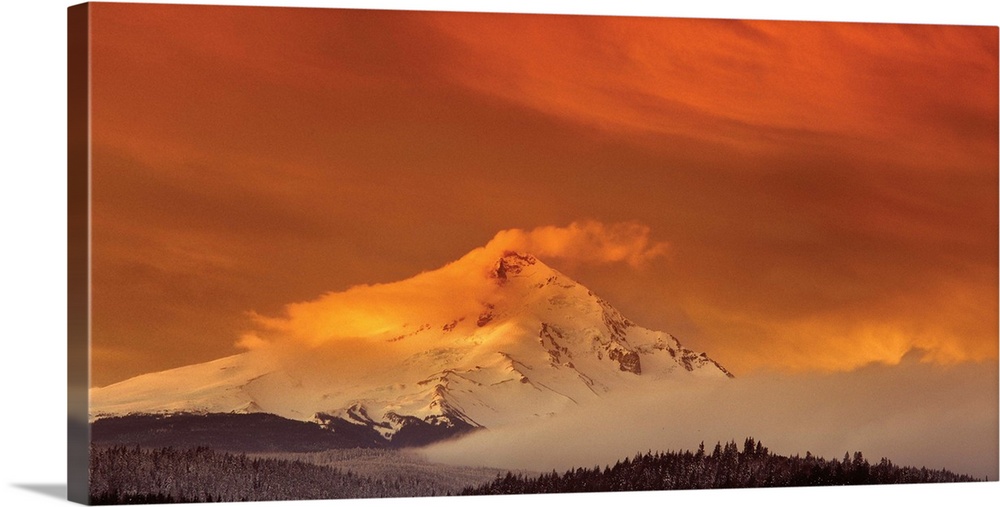 Clouds covering the snowy peak of Mount Hood at sunset.