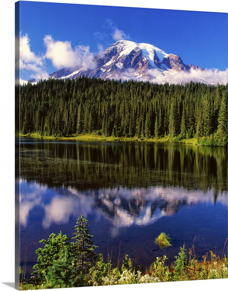 Mount Rainier surrounded by clouds seen from a lake.