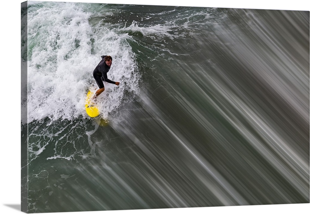 Action photograph of a person surfing on a wave with a bright yellow surf board in Oceanside, California.