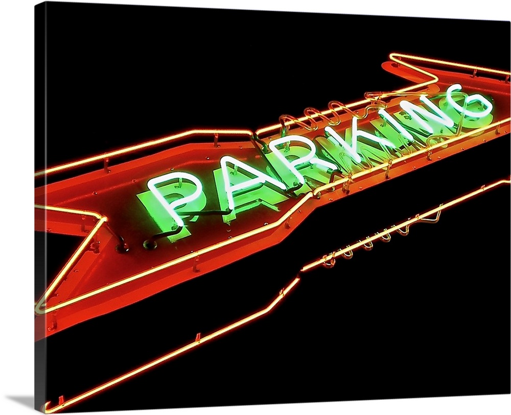 Photograph of a red and green neon arrow sign lit up at night that reads "Parking"