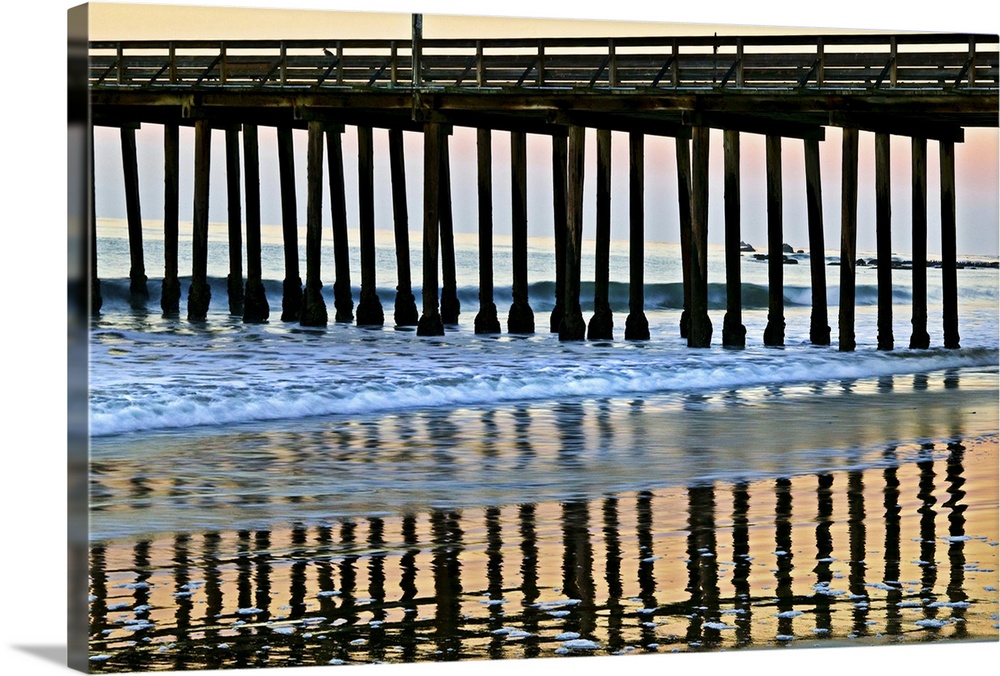 Cayucos Pier silhouette and reflections onto the water at sunset.