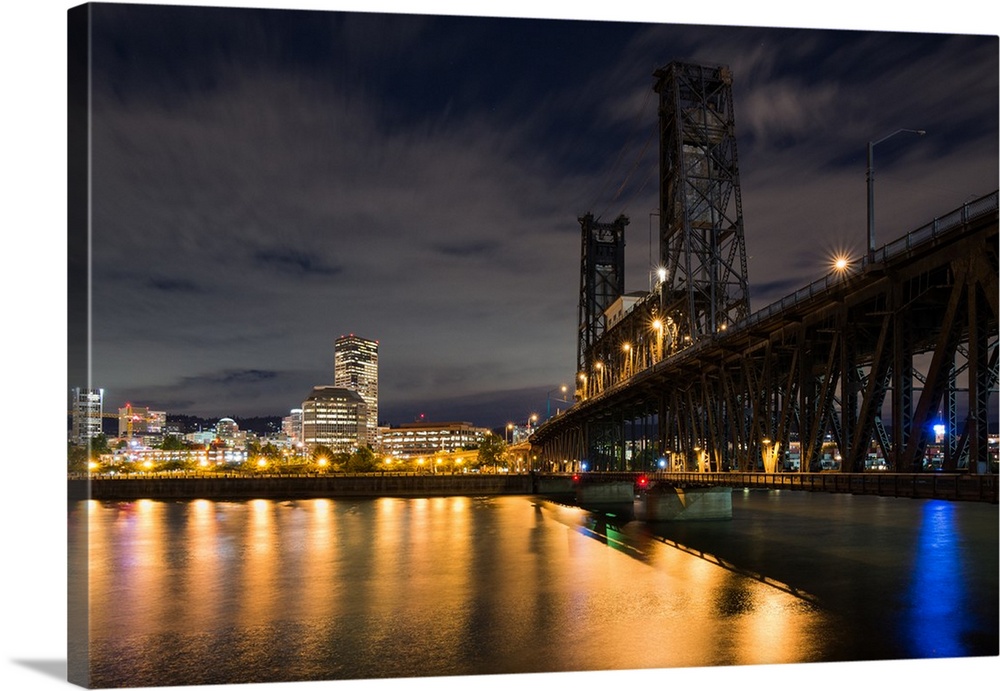 Photograph of Portland lit up at night with the Willamette River in front and the Steel Bridge on the side.