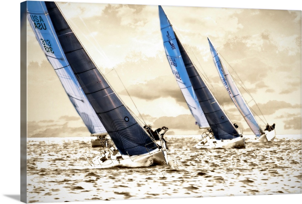 A photograph of three sailboats speeding through the water on a sunny day; this wall art has a bright monochromatic sea an...