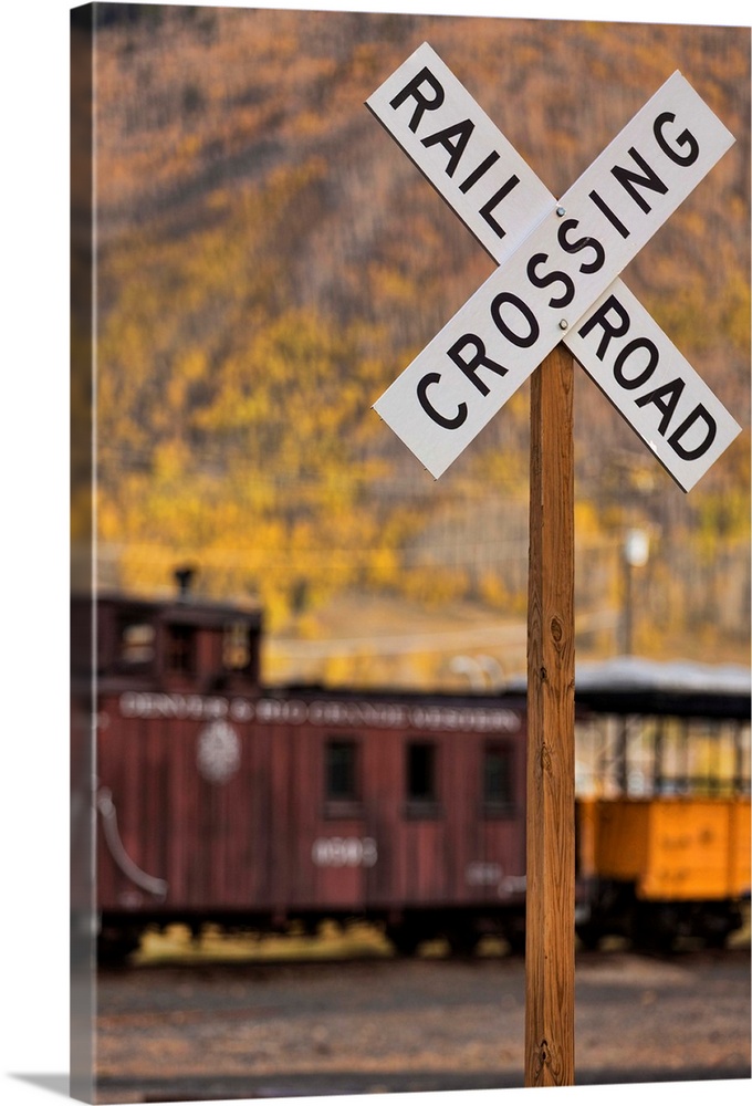 Photograph of a railroad crossing sign in front of a vintage train car.