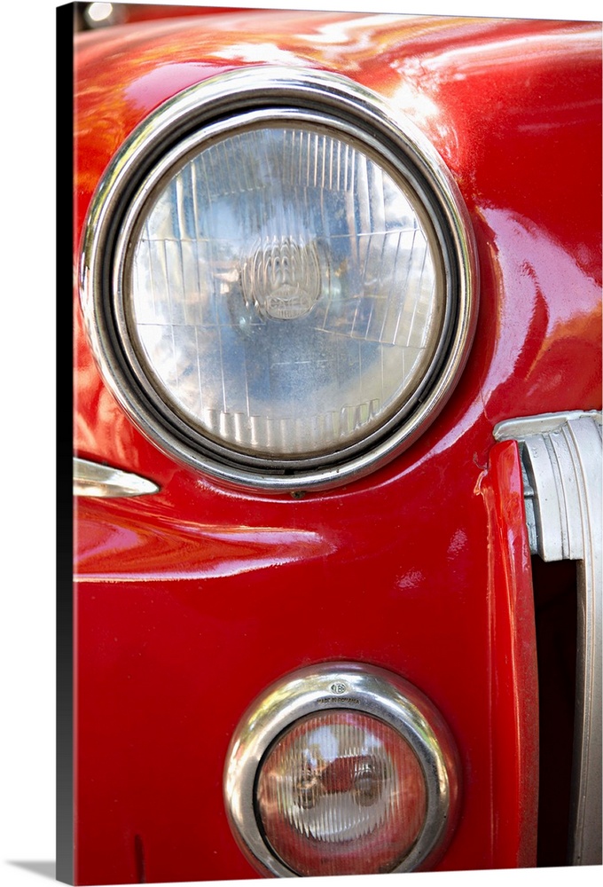 Close-up photograph of the headlight of a red vintage car in Cuba.