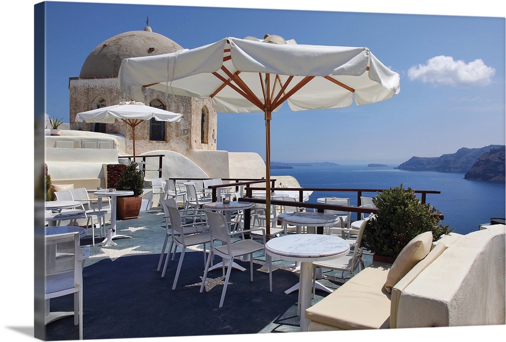 Open air restaurant on deck with adjacent church overlooking caldera in Santorini, Greece