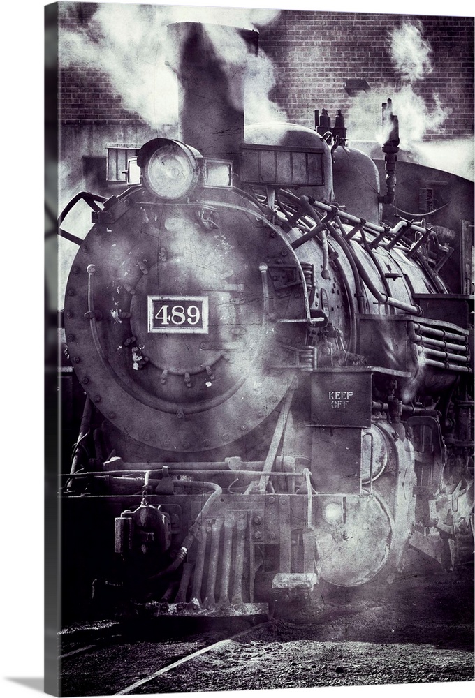 Photograph of a vintage locomotive covered in steam on the train tracks.