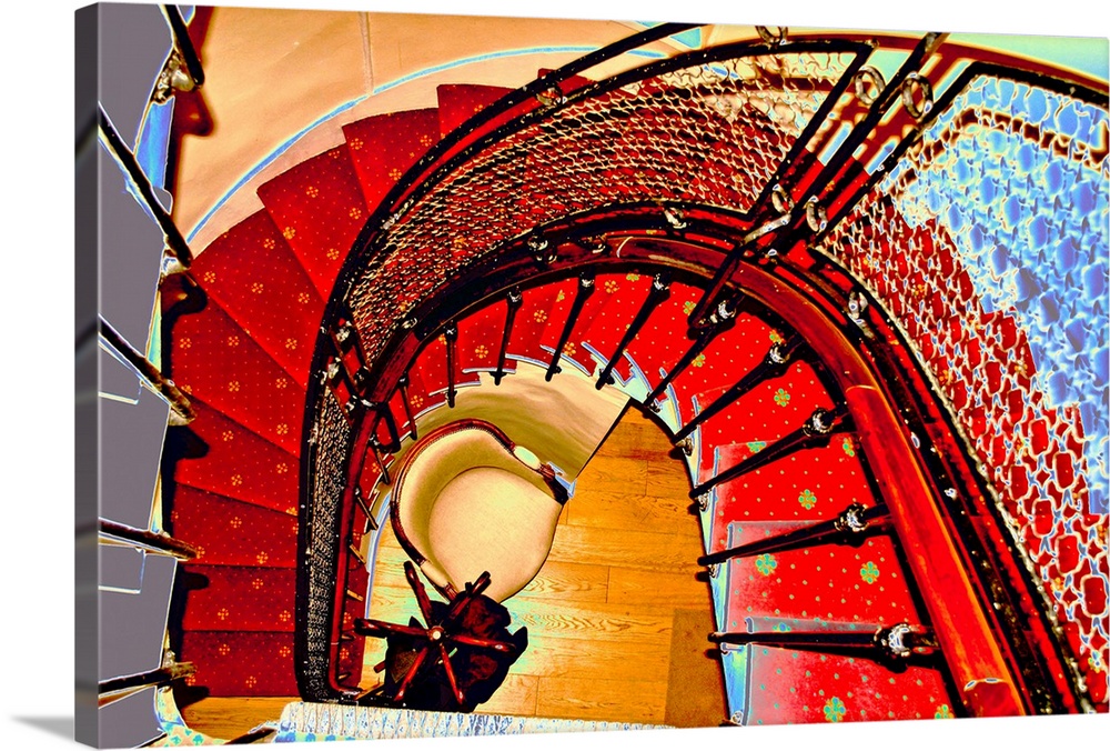 Giant photograph taken of a vibrantly colored metal staircase as it curves in-between floors.  At the bottom of the stairc...