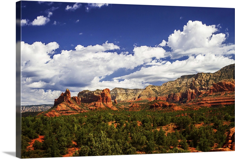 Landscape photograph of rock formations and big white clouds in the blue sky over Sedona, Arizona.
