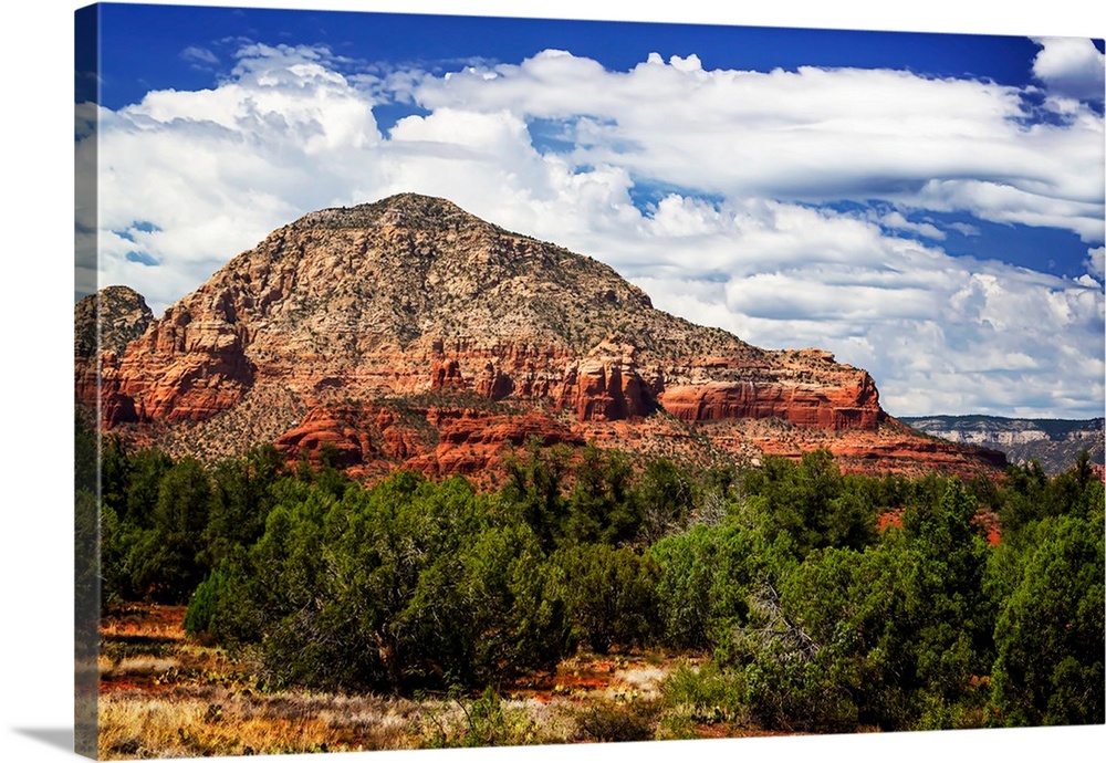 Landscape photograph of a rock formation in Sedona under blue, cloudy skies.
