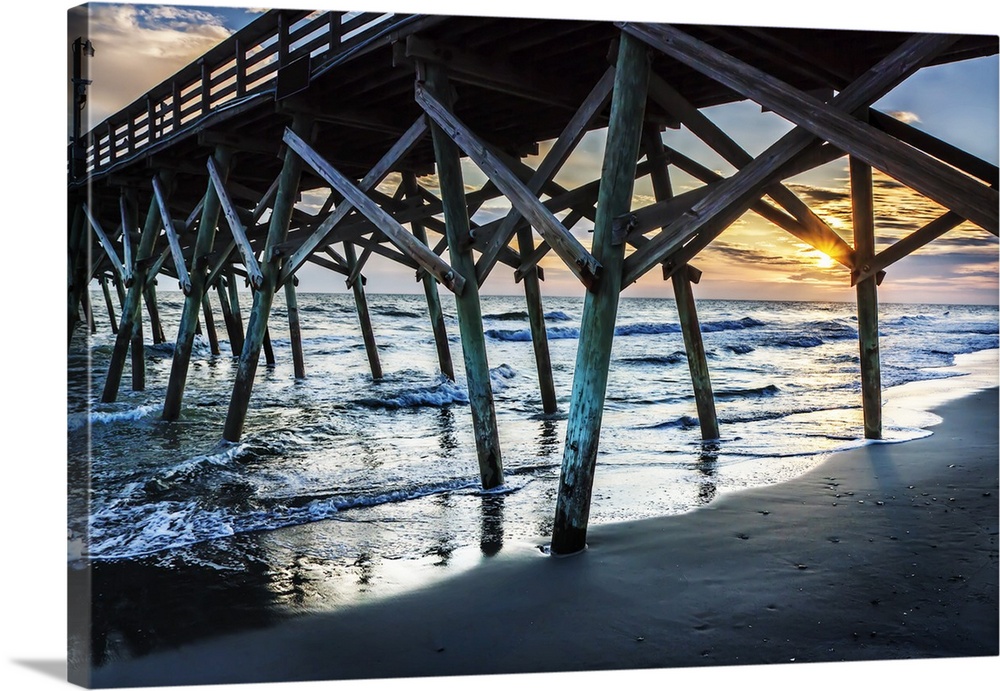 View of a sunrise over the ocean from underneath a wooden pier.