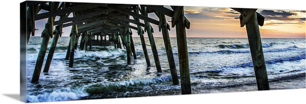 Wooden piers in the ocean silhouetted at sunset.