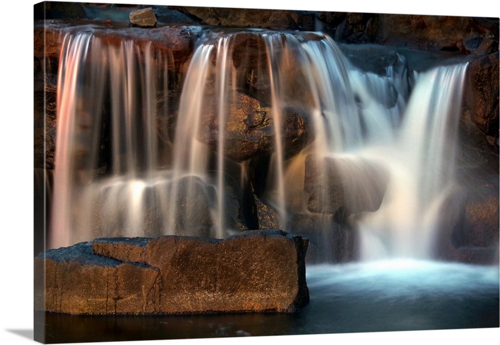 Long exposure photograph of a waterfall lit with warm light from the sunset.