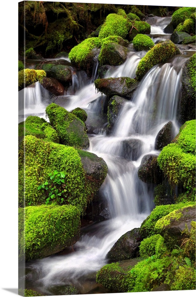 Long exposure photograph of a rocky waterfall lined with bright green moss covered rocks.