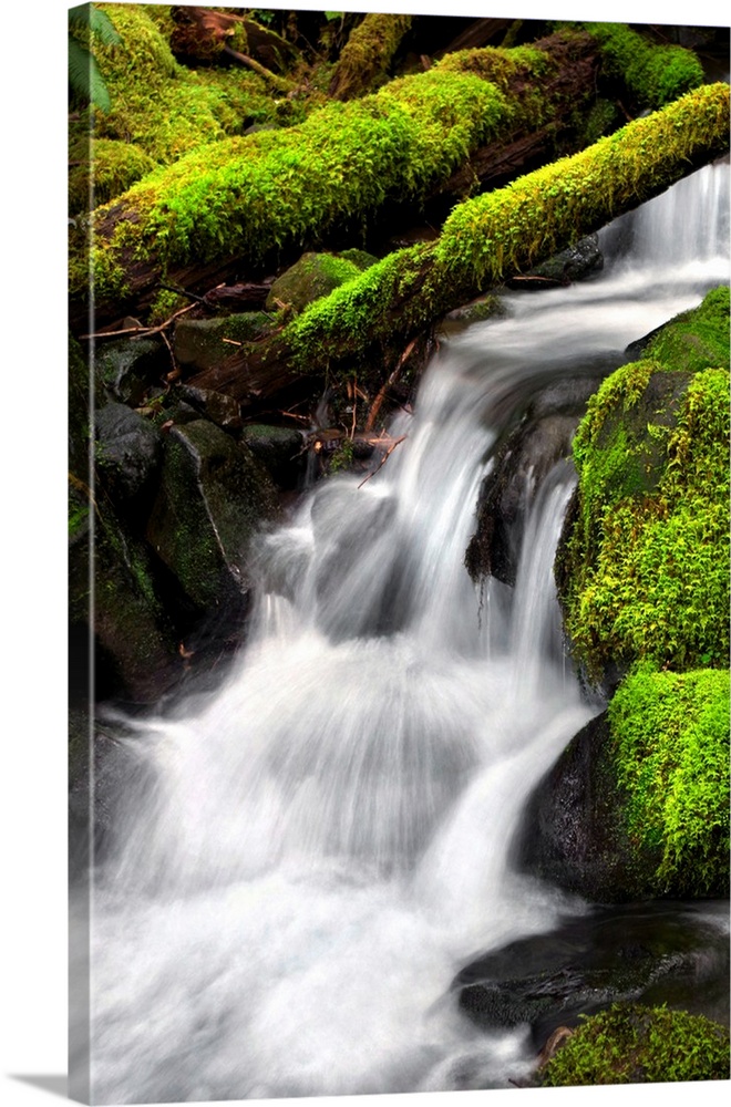 Long exposure photograph of a rocky waterfall lined with bright green moss covered rocks.
