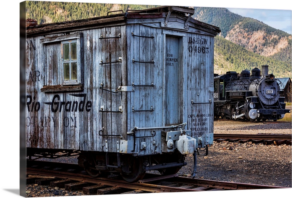 Photograph of a vintage train car on the railroad tracks.