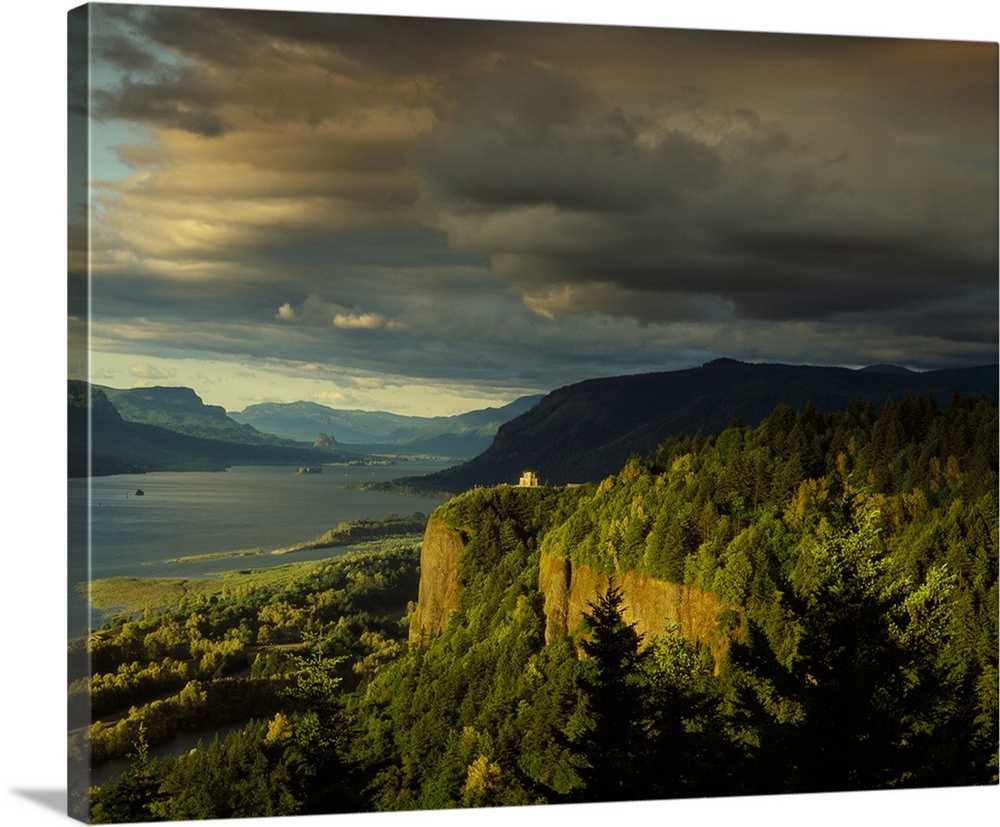 Photograph of the Columbia River lined with hills and the Vista House in the distance at golden hour.