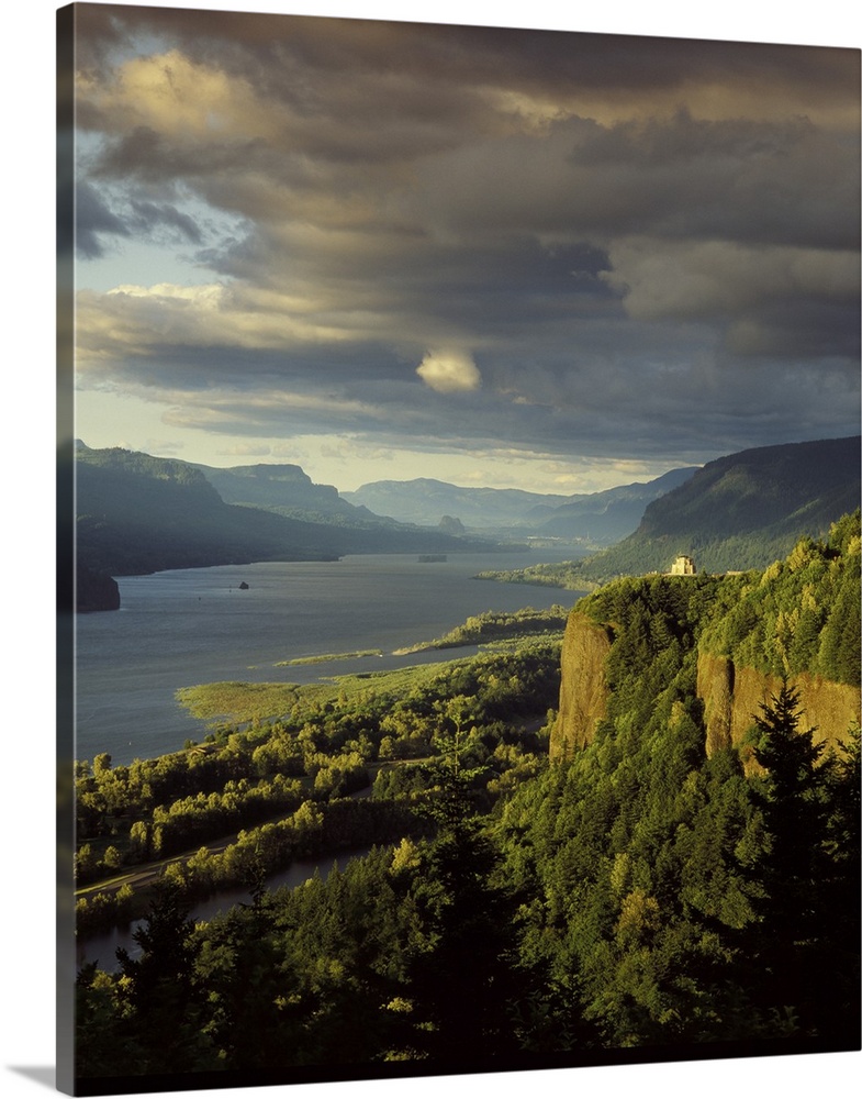 Photograph of the Columbia River lined with hills and the Vista House in the distance at golden hour.