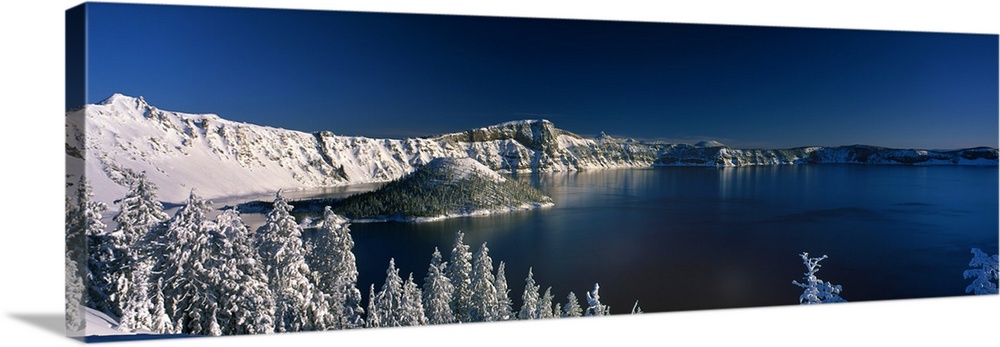 Panoramic photograph of Crater Lake surrounded by snow covered mountains in Crater Lake National Park, Utah.