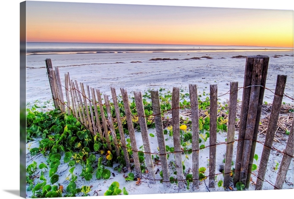 Wall art for the home or office this landscape photograph is of a battered barrier fence ends on the edge of the sandy sho...
