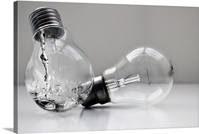 A black and white image of two light bulbs, one containing running water.