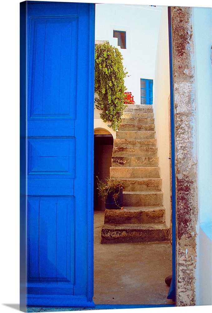 A blue door leading up a stairwell in Greece