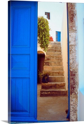 A blue door leading up a stairwell in Greece