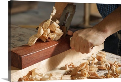A carpenter using a block plane, shavings on the table