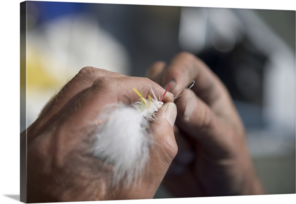 A close-up view of hands tying a fly to fishing line.