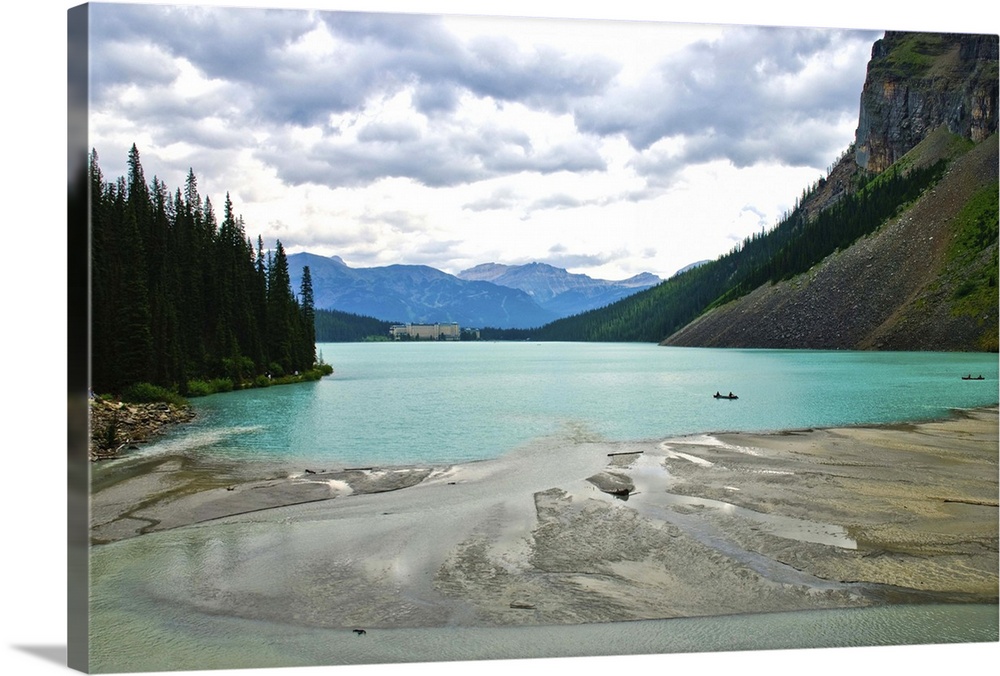 Looking across a sandbar to the calm turquoise waters of Lake Louise, Banff National Park, Canada. In the distance, a summ...