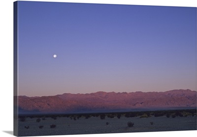 A moon above a mountain range in Death Valley National Park