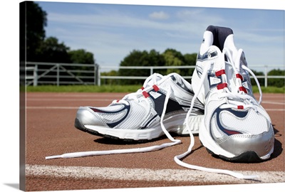 A pair of new white running trainers are placed on a running track