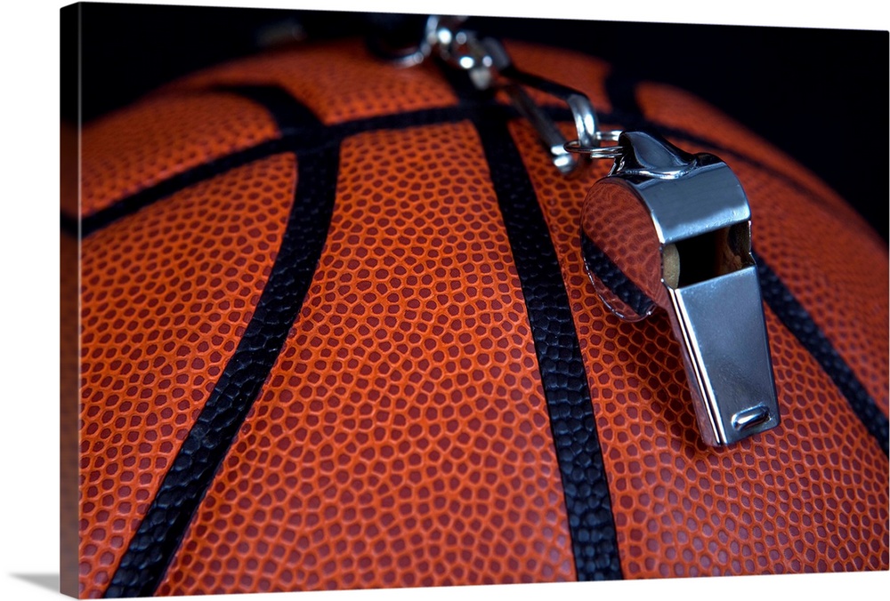 A referee's whistle rests on top of a basketball.  Shot with Canon 5D Mark II.