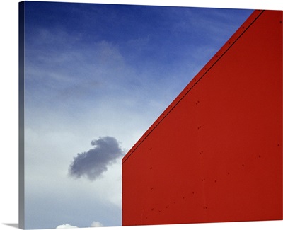 A shadowed cloud floating through blue sky over the red corner of James John School.